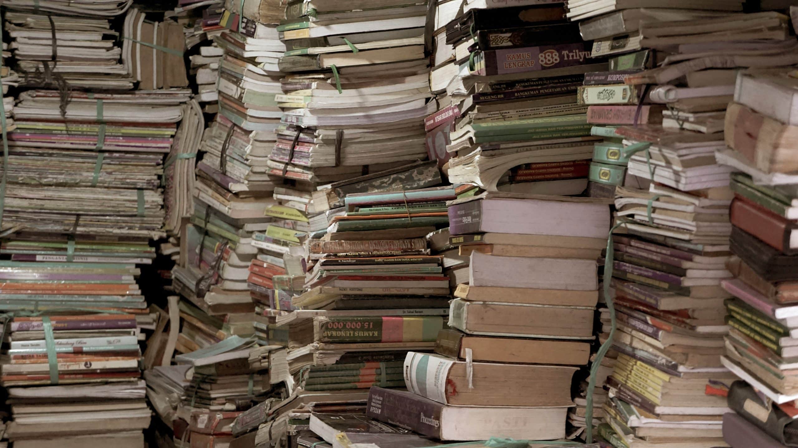 Huge piles of old books of paper, representing the inefficiencies in the processes